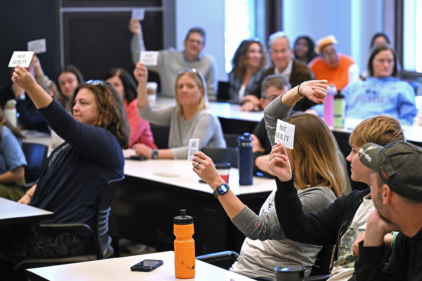 Participants hold up not-guilty verdict cards at a mock trial activity during Fall Weekend 2024