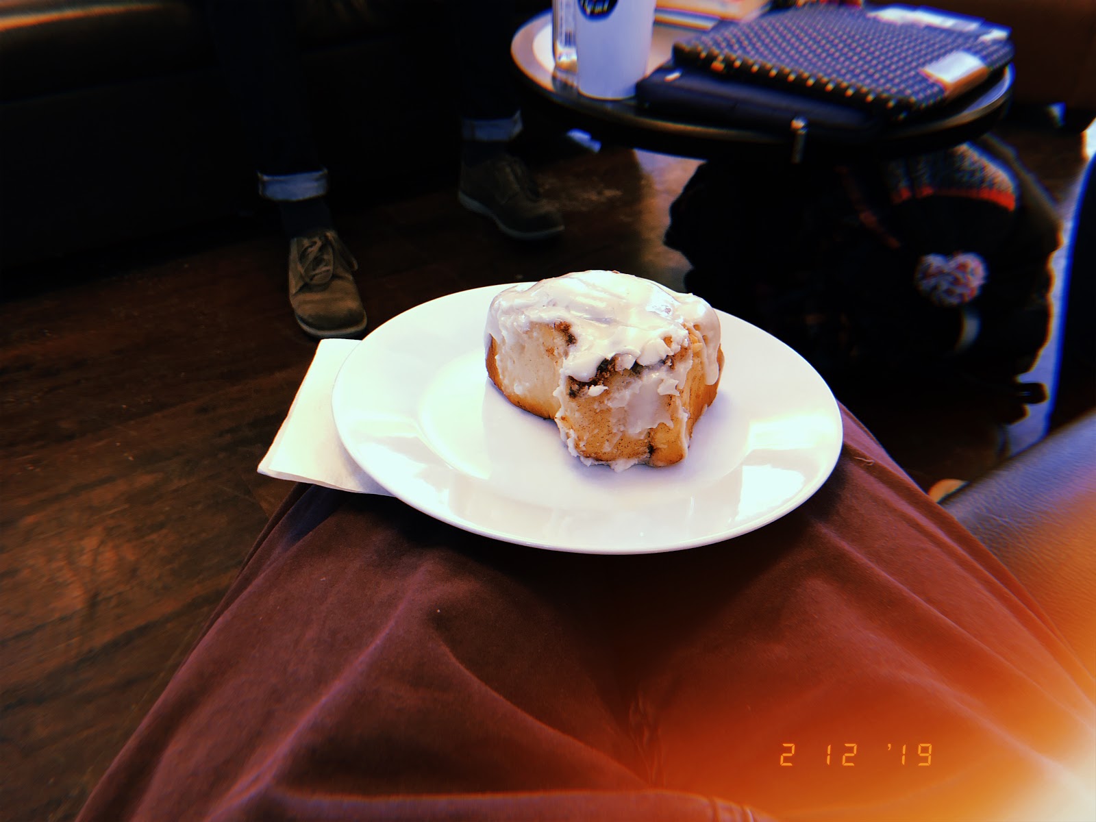 A glazed cinnamon bun from the Walk-In Coffee Closet rests on top of a white plate
