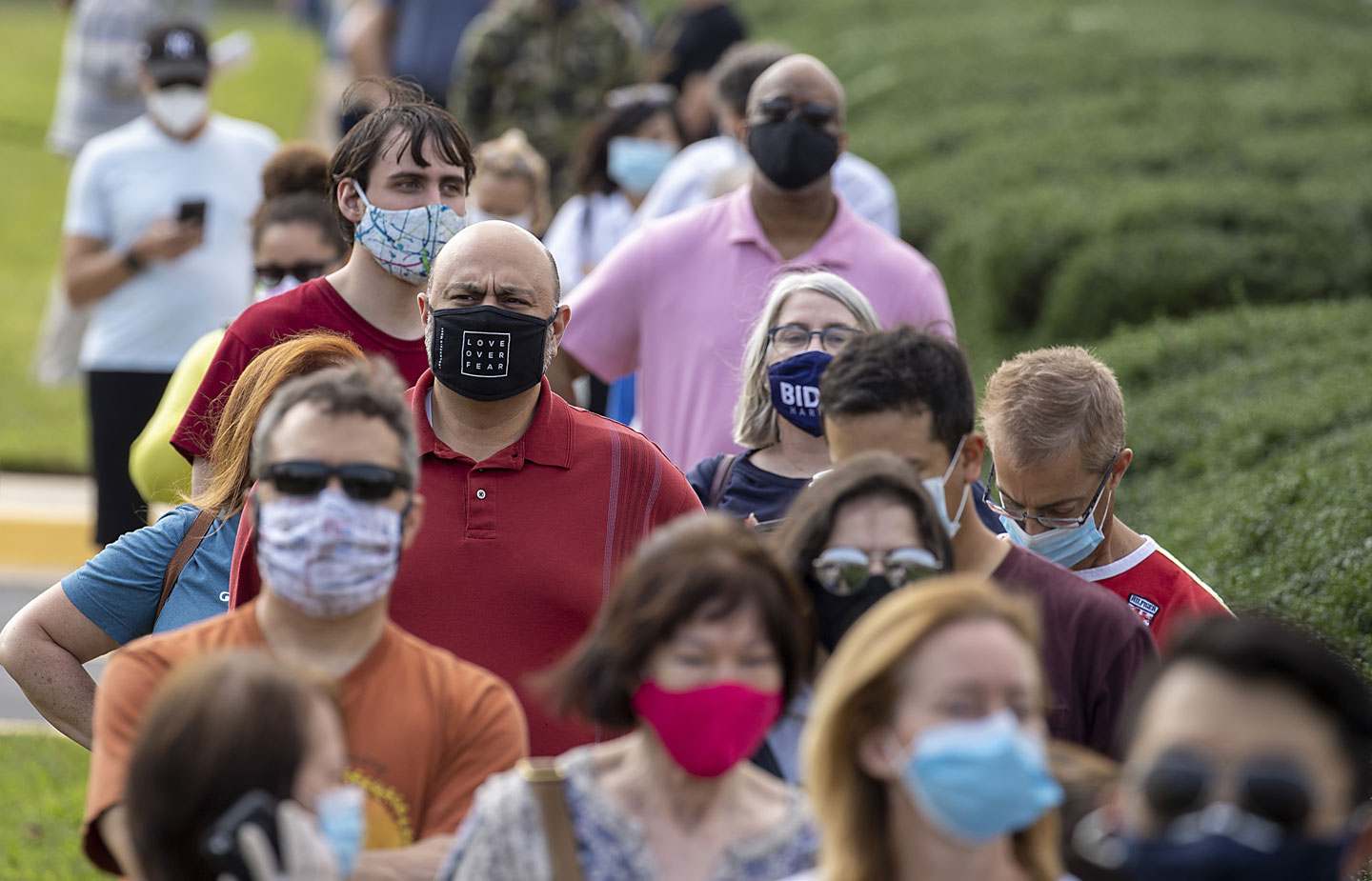 Image of people waiting in line to vote wearing masks