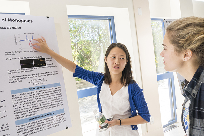 A student explains her research while pointing to her poster about her project. 