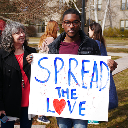 A.T. Thomas ’20 holds a sign at the Feb. 8 stand in as Associate Professor of Music Midge Thomas looks on. 