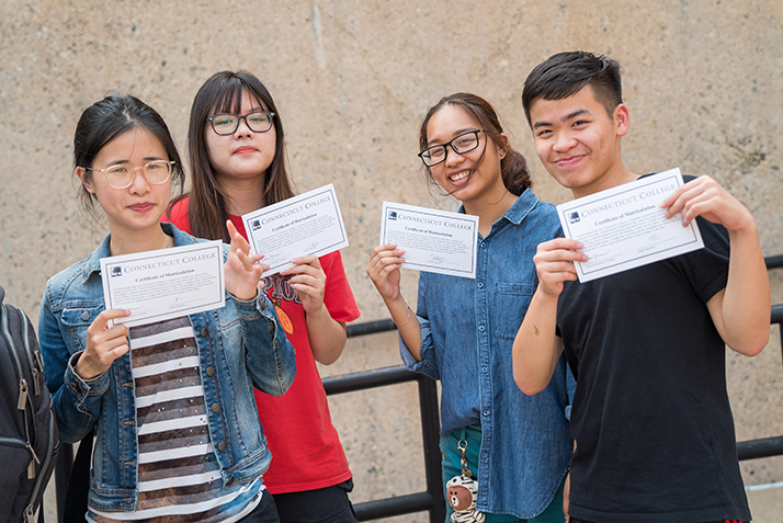 Four students pose with their certificates of matriculation. 