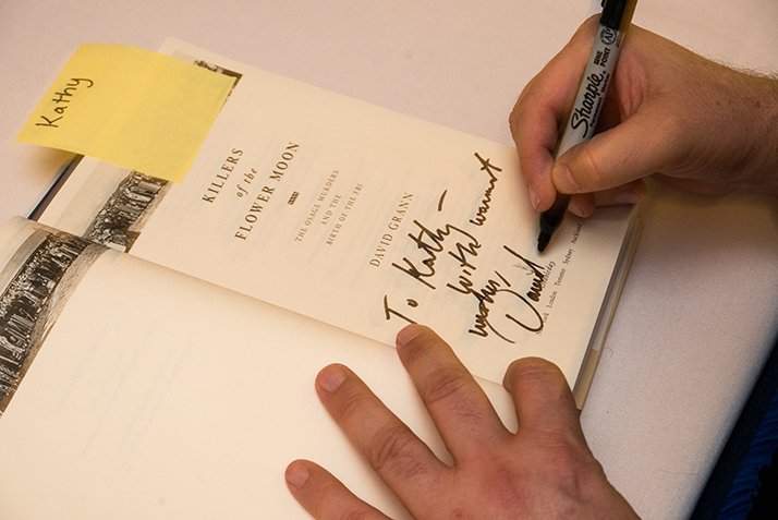 A close up of David Grann signing books after his President's Distinguished Lecture Series lecture.