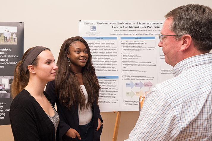 A professor listens as two students describe their science research. 