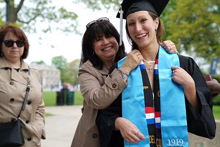 A graduate prepares for the ceremony with a family member