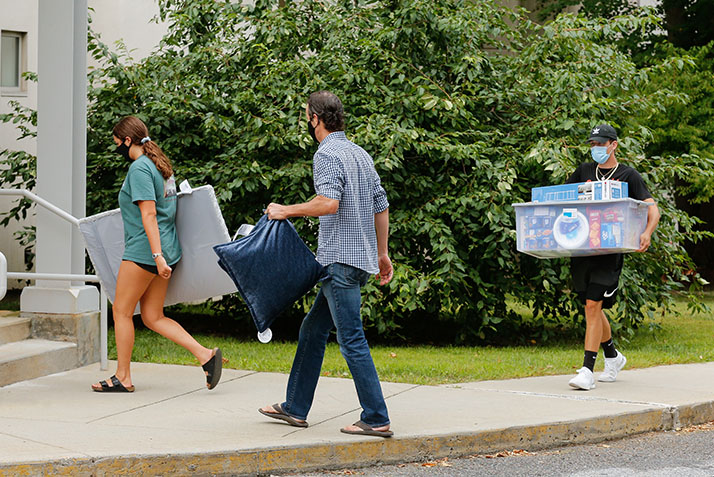 Students and their families carry boxes into a dorm