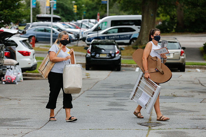 A student and a family member carry belongings toward the dorm