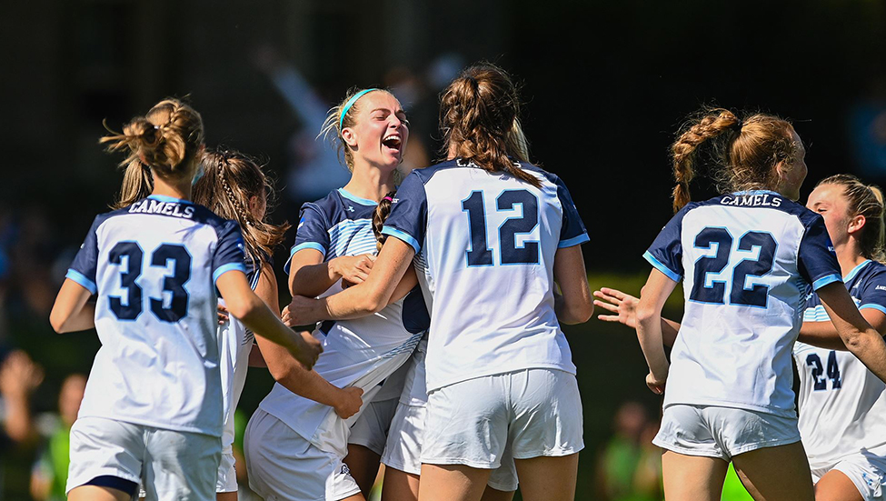 Members of the women's soccer team celebrate after a goal.