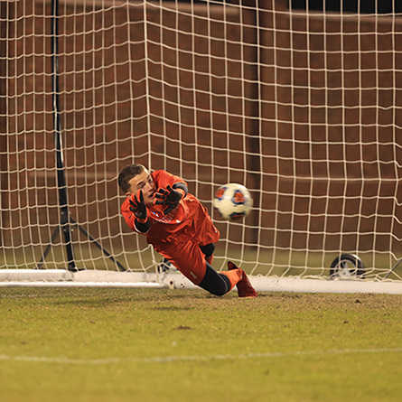 The goalie makes a save on a penalty kick attempt. 