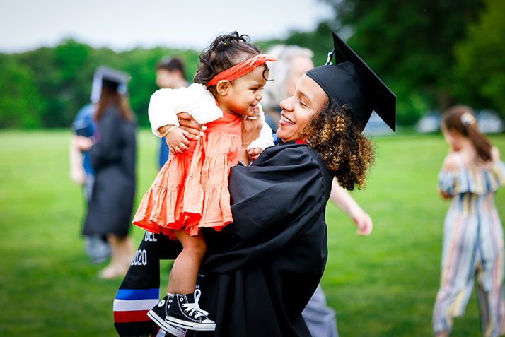 A graduate embraces a toddler.