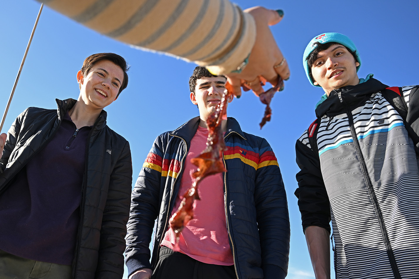Prof. Maria Rosa shows Abigail Haan ’26, Jamie Sussman ’26, and Kian Miranda-Rodriguez ’26, seaweed found on the sand during a research trip to Waterford Town Beach in February.
