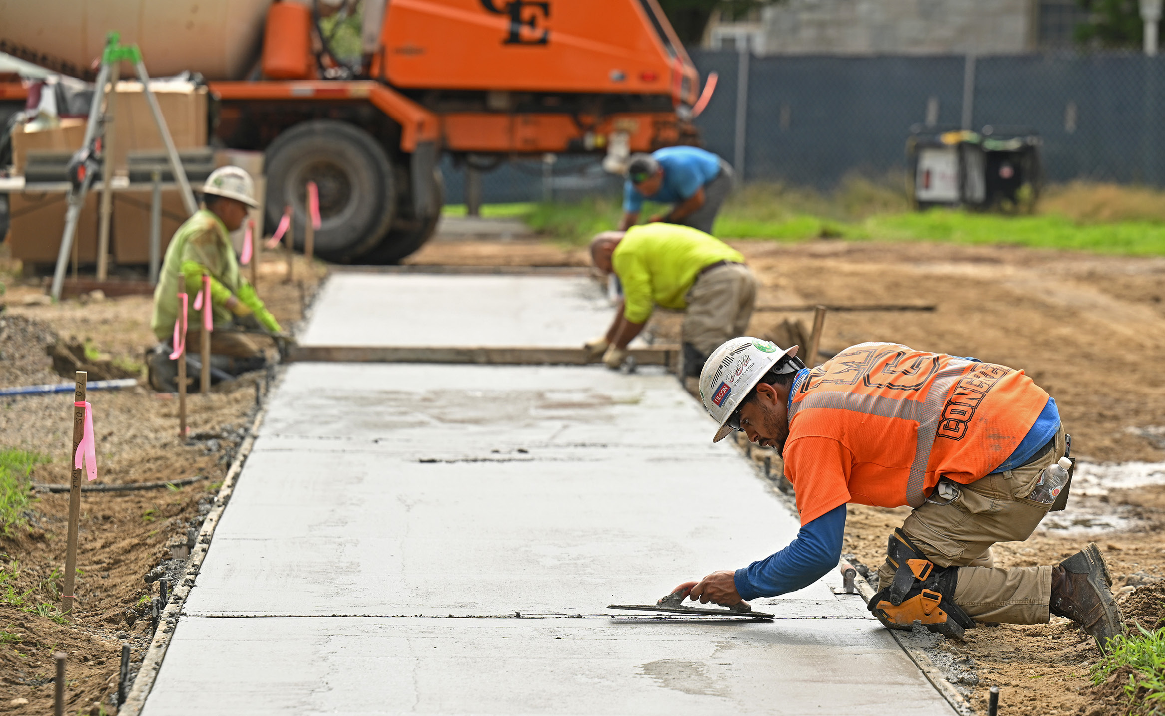Workers level fresh cement on a campus sidewalk