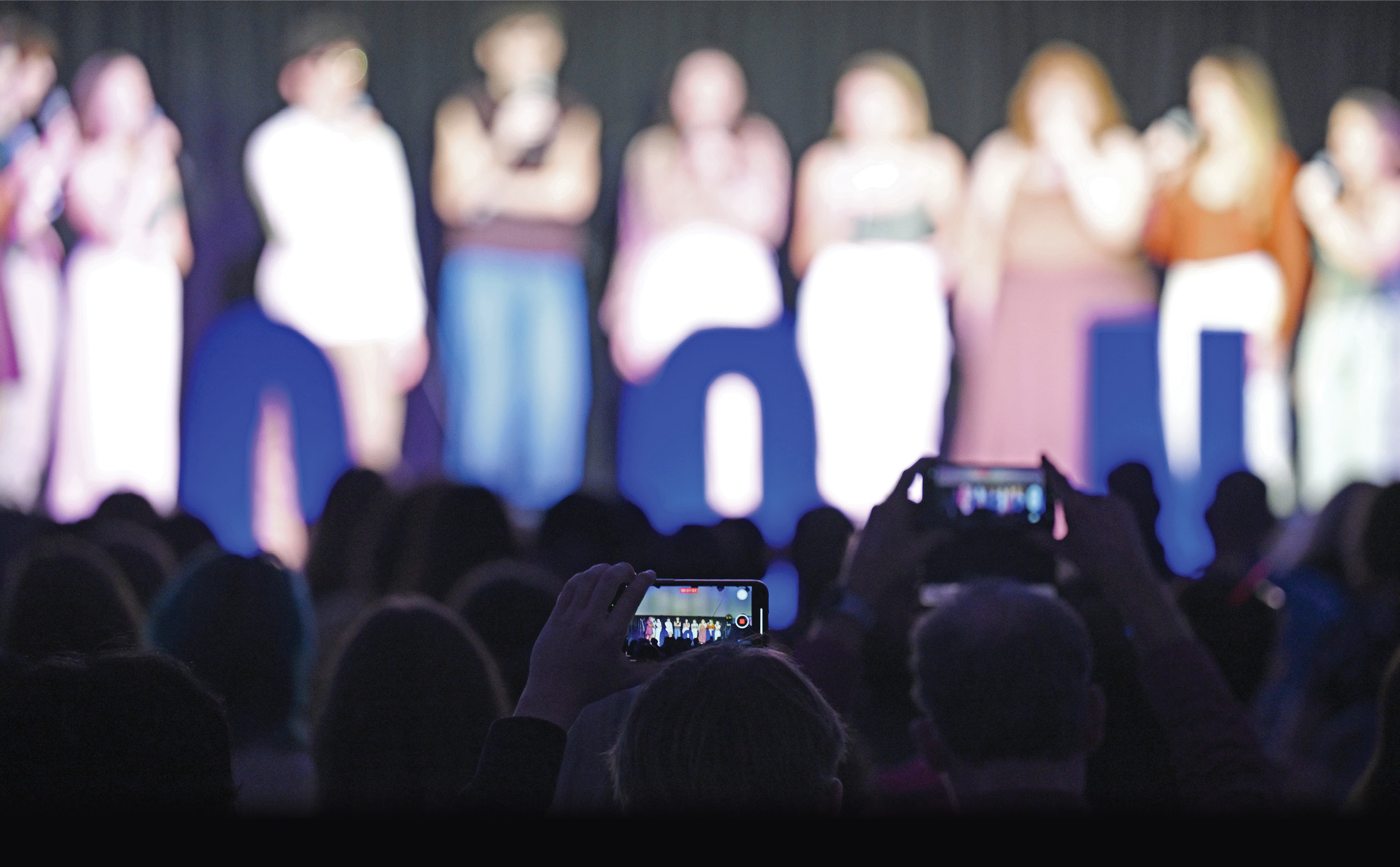 A crowd records an a cappella performance in their smart phones at Fall Weekend 2023.