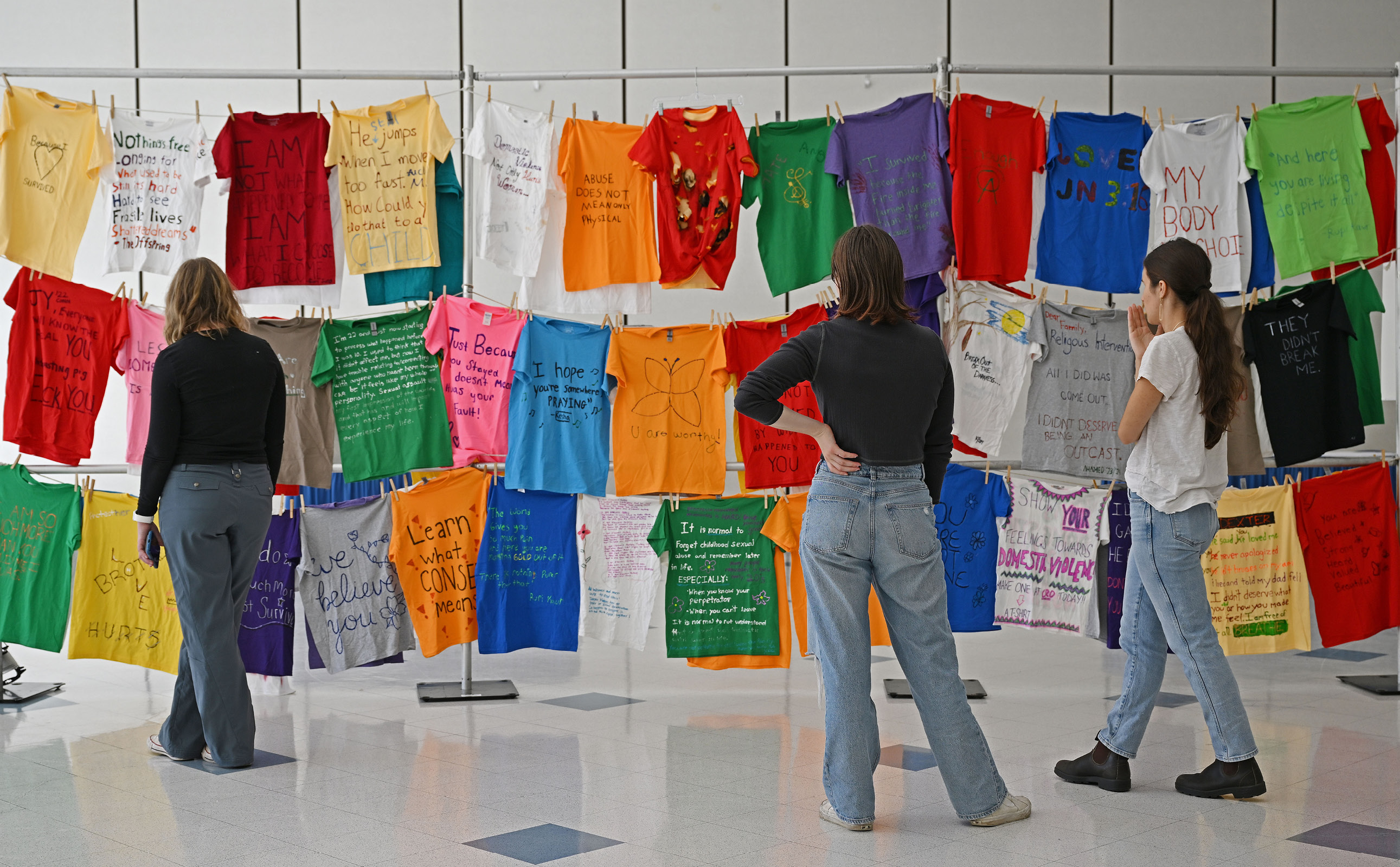 Students view handwritten shirts at the Clothesline Project in the 1962 Room.
