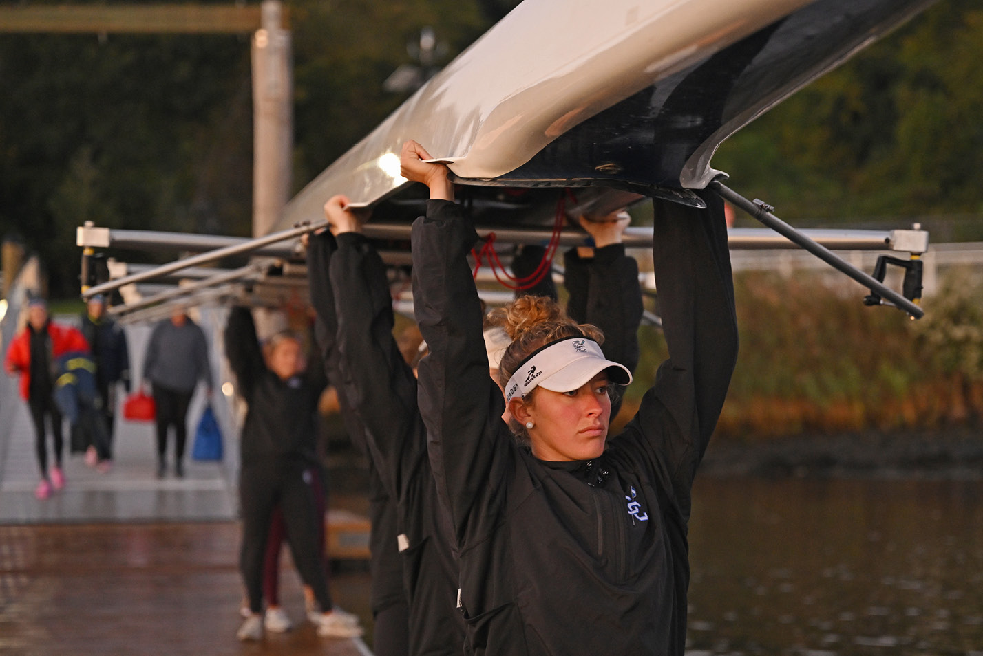 Womens crew hauls boats on the Thames River at dawn in October.
