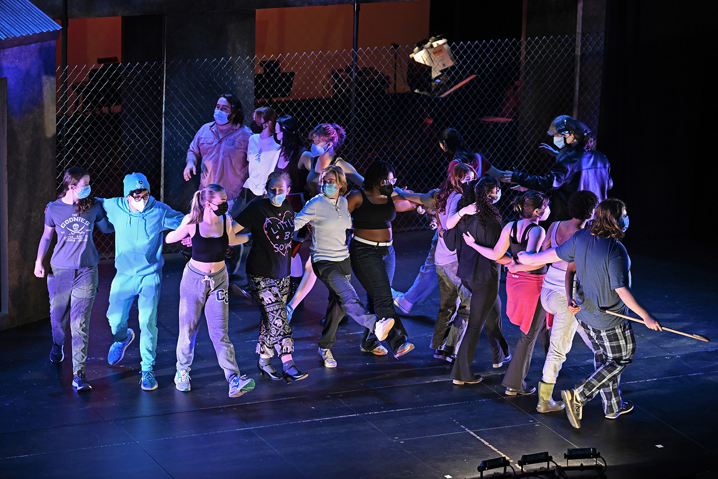 actors dance around on stage in big x formation