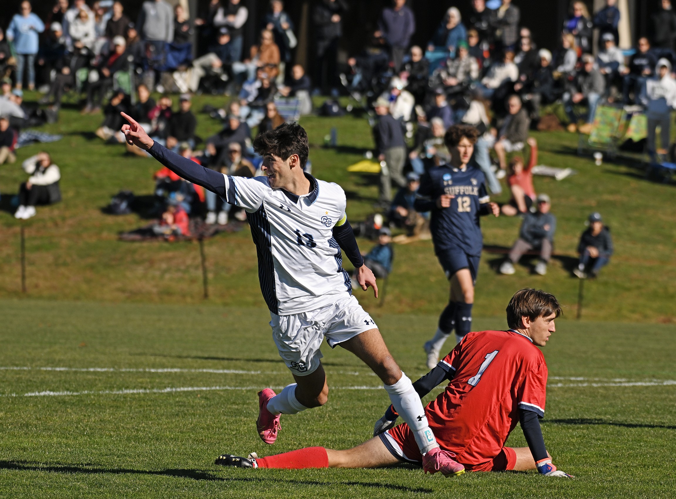 A soccer player raises his hand in celebration after scoring a goal in a playoff game.